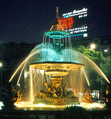 1968 TAP airline commercial in lights behind  the fountain in  Rossio Square, Lisbon, Portugal – Best Places In The World To Retire – International Living